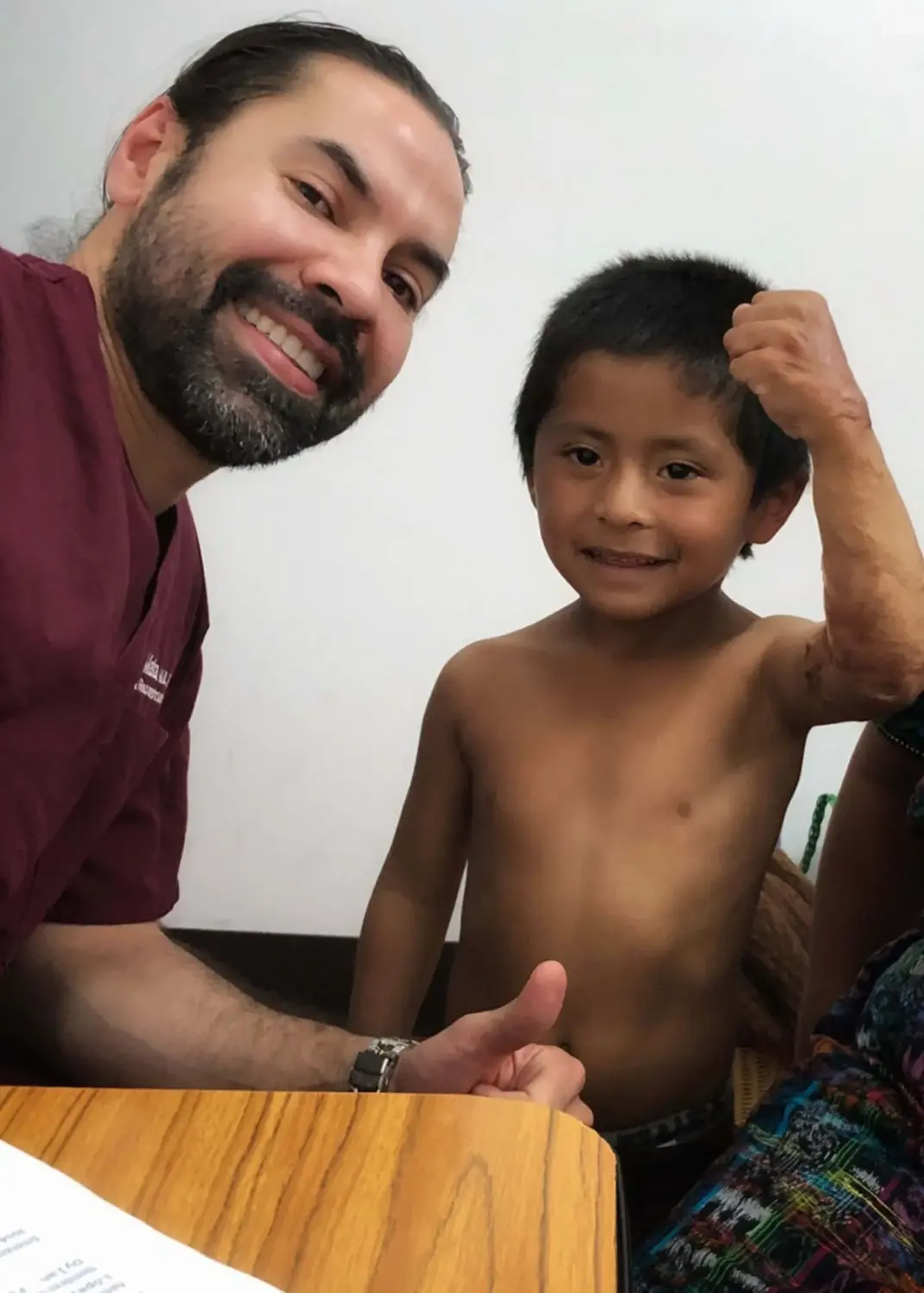 Dr. Mata with a young patient in a hospital gown after surgery
